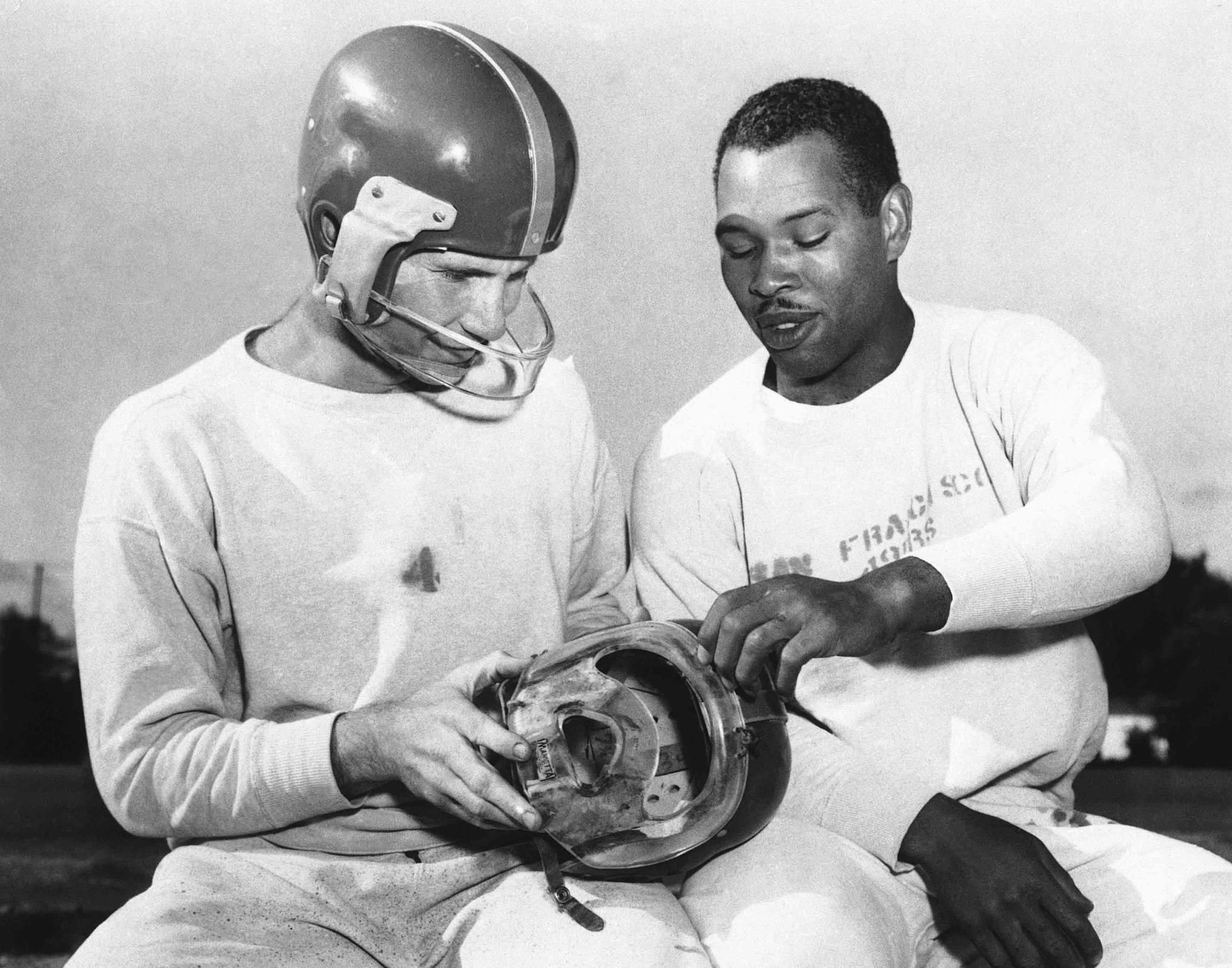 San Francisco 49ers fullback Joe Perry, right, shows quarterback Y. A. Tittle the plastic mask he has worn during the football season to protect his bridgework, during practice at Menlo Park