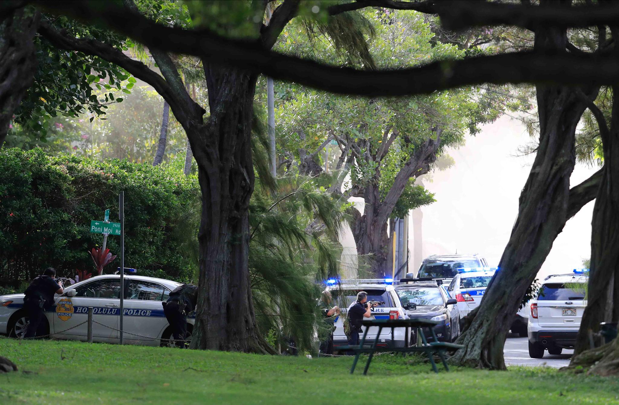 Honolulu police take up defensive positions with their weapons after a shooting and domestic incident at a residence on Hibiscus Road near Diamond Head