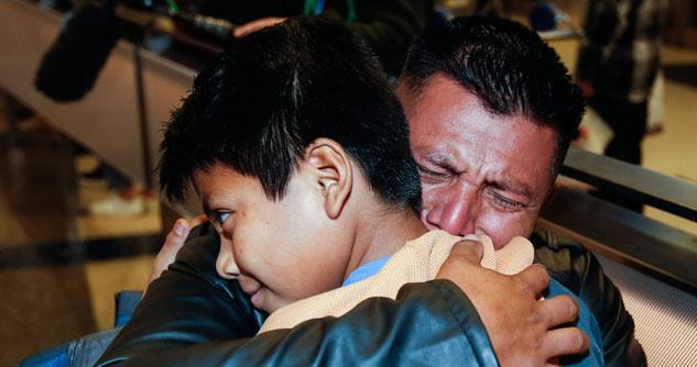 Man tearfully hugging his son for the first time in two years.