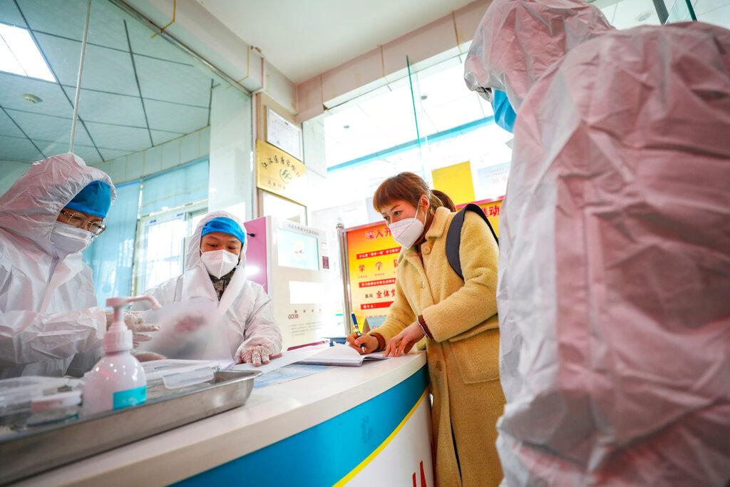 Medical workers in protective gear talk with a woman suspected of being ill with a coronavirus at a community health station in Wuhan in central China's Hubei Province