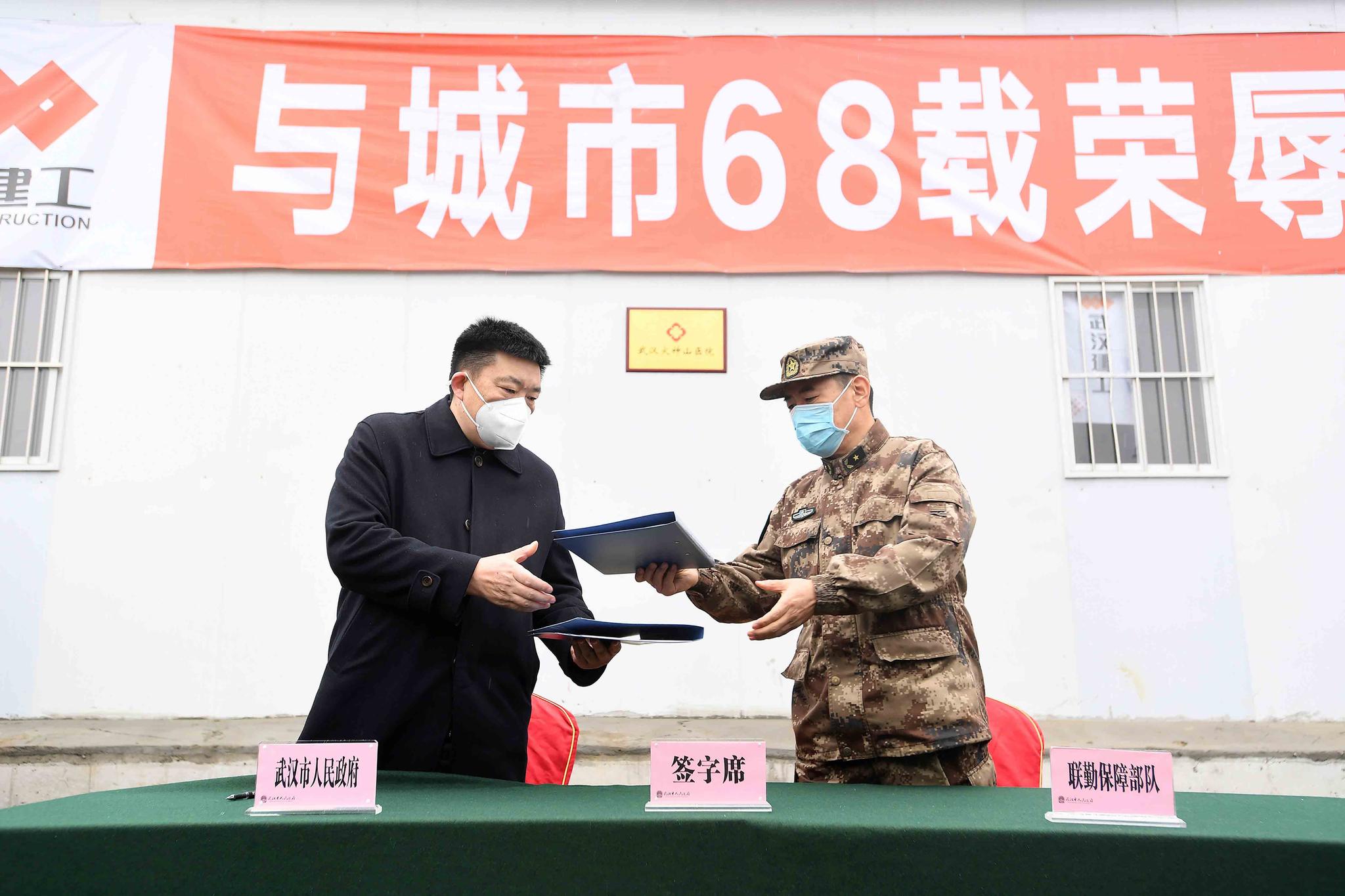 Zhou Xianwang, left, the mayor of Wuhan, exchanges documents with Bai Zhongbin, right, deputy commander-in-chief of China's People's Liberation Army (PLA) Joint Logistic Support Force, during a handover ceremony at the Huoshenshan temporary field hospital in Wuhan in central China's Hubei Province