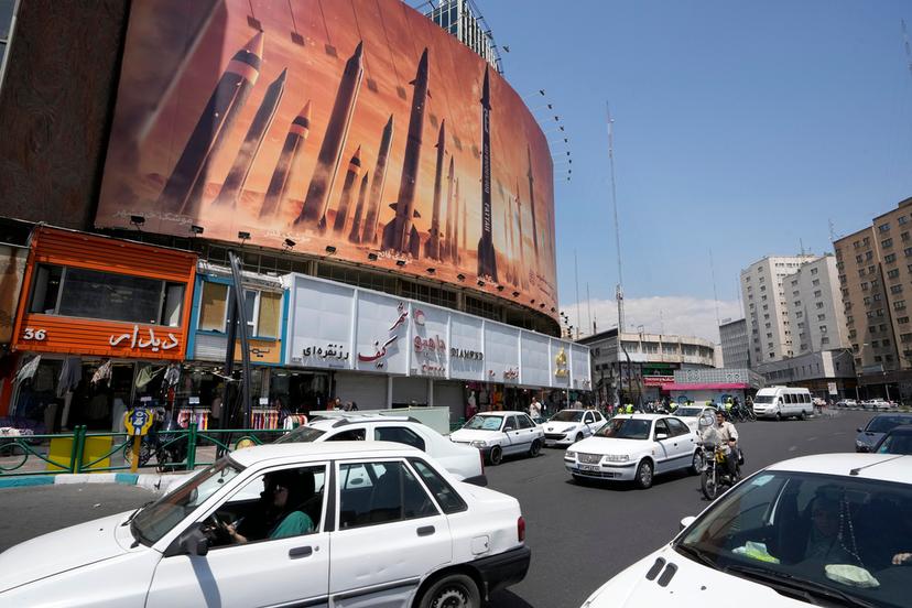 Vehicles drive past an anti-Israeli banner showing missiles being launched, in a square in downtown Tehran, Iran, Friday, April 19, 2024.