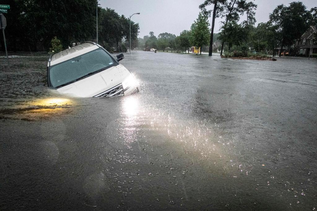 An SUV is stranded in a ditch in a stretch of street flooding during a severe storm